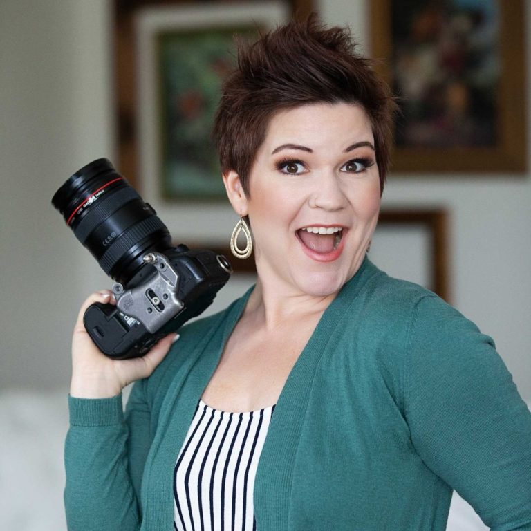 Energetic professional photographer smiling and holding a camera, captured in a bright studio environment — Boudoir Defined photography studio in Meridian, Idaho